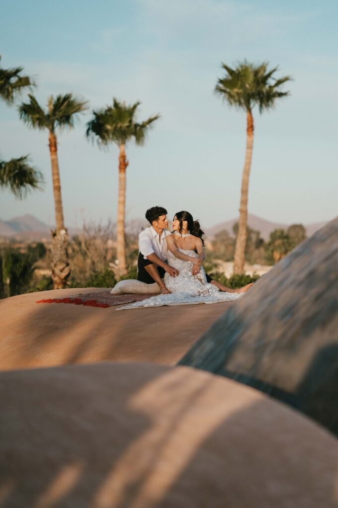 Couple sitting on berber rug and kissing on Palais Namaskar's rooftop.