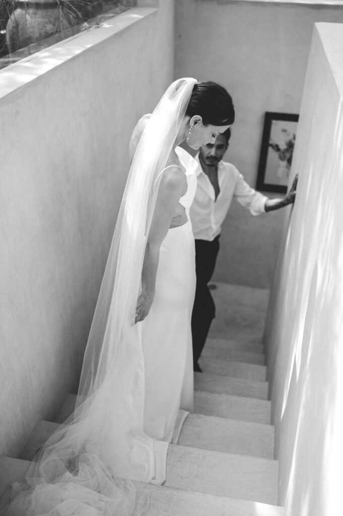 Vogue inspired black and white photograph of bride and groom holding hands before their Tulum elopement. 