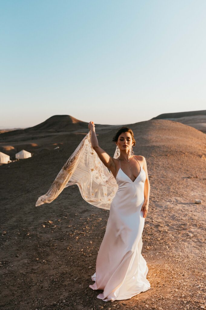 Megan standing in the desert at Be Agafay wearing Rue de Seine Palm Haze dress and Desert Rose Veil.