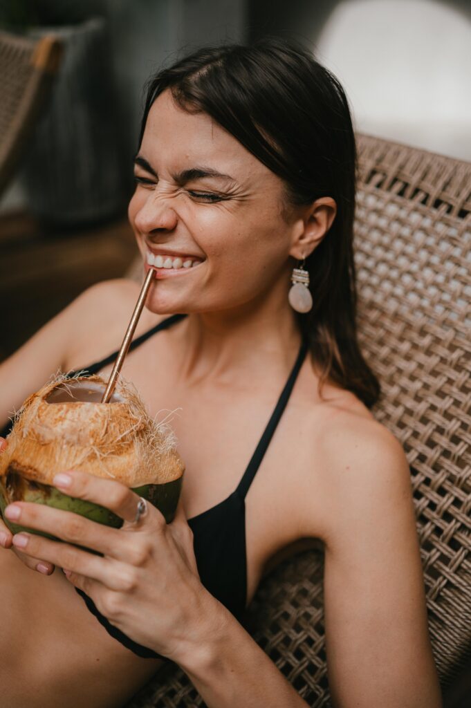 Bride smiling and sipping coconut water on the morning of her Tulum intimate wedding. 