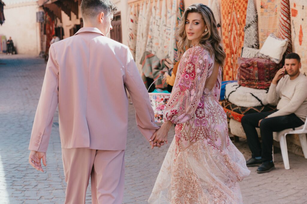 Lisa and Paul holding hands and walking in the Medina. Marrakech destination photographer Sarah Hurja. 