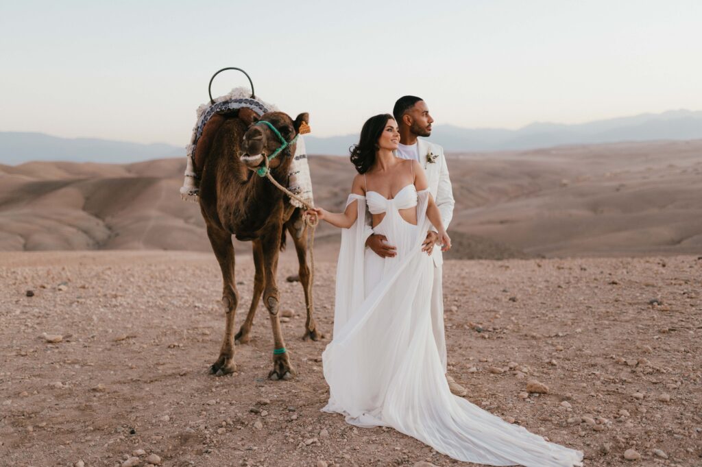 James and Megan wearing Rue de Seine gown with camel in the Moroccan desert. 