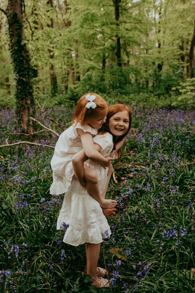 Two red hair sisters playing in the bluebell woods in Hampshire woods. 