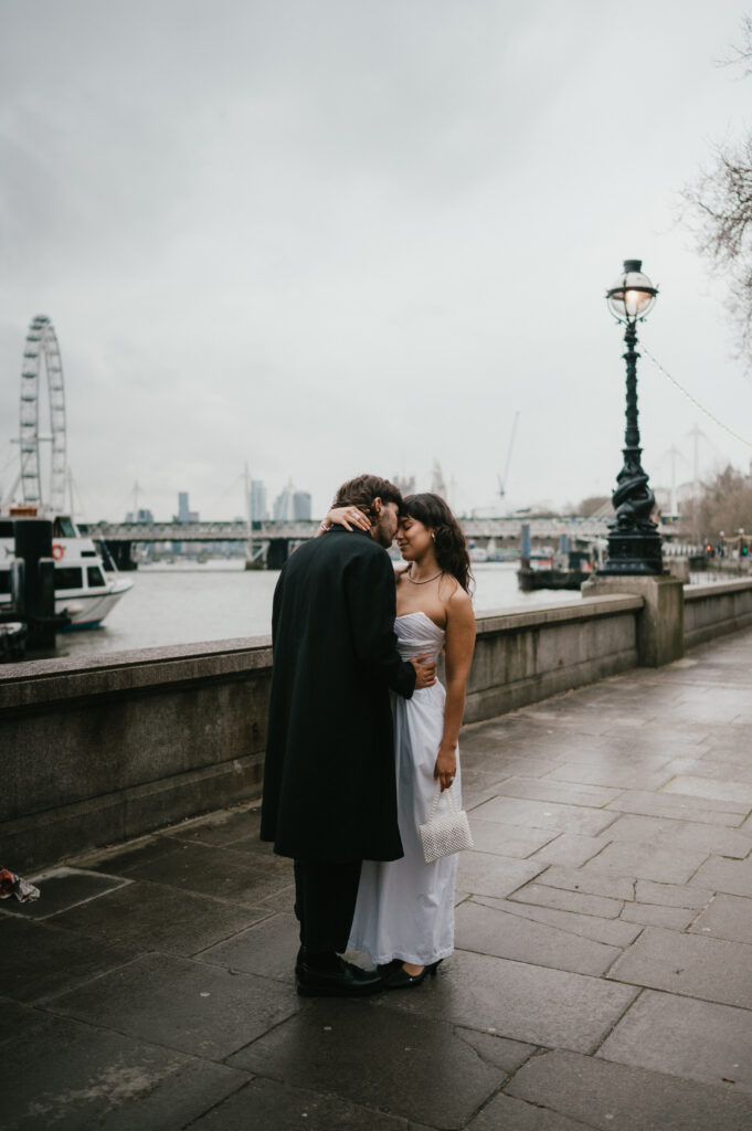 Bride and groom kissing by the thames river London. 