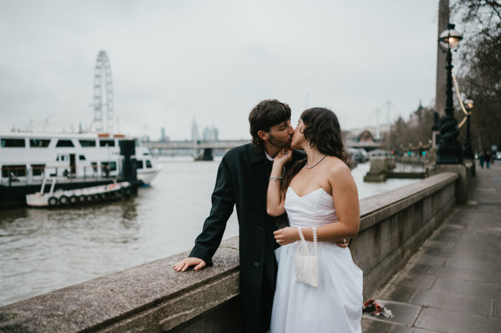Maggie and Angus kissing after their London elopement with the London Eye as their backdrop.