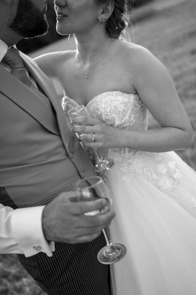 Black and white close up of Amanda and John's hands holding champagne flutes.