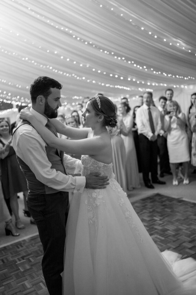 Amanda and John sharing their first dance at the reception, surrounded by family and friends.