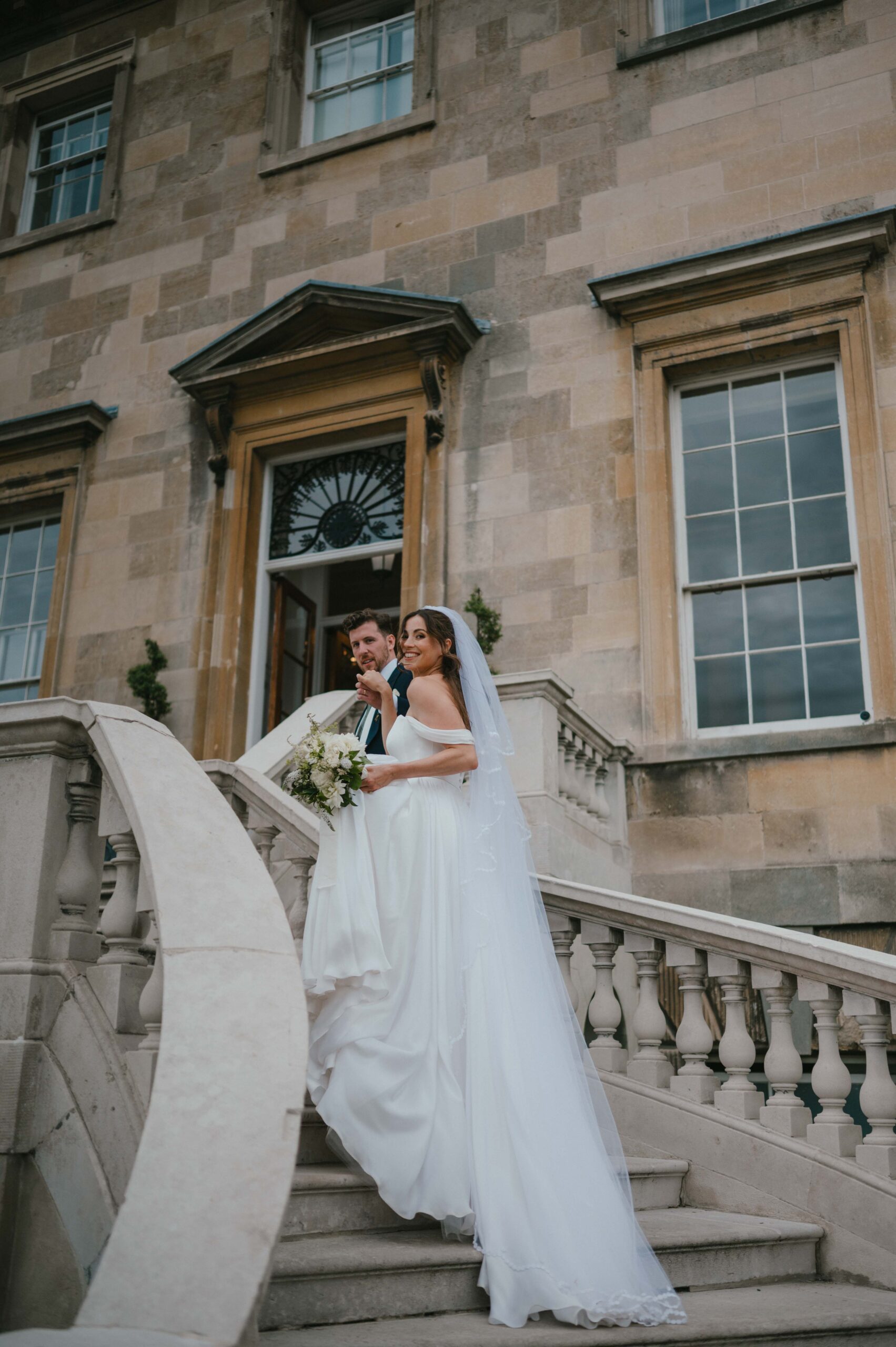 Charlie and Martin strike a confident, editorial pose on the sweeping staircase, capturing the essence of modern elegance.