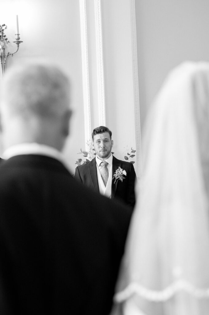 Black and white close up of Martin crying, frame in between the back of Charlie and her father.