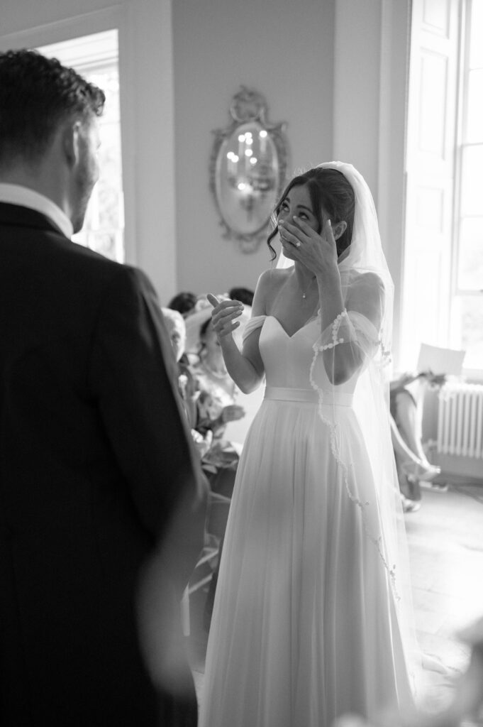 Black and white photo of the bride, Charlie, wiping away a tear as Martin read his vows.