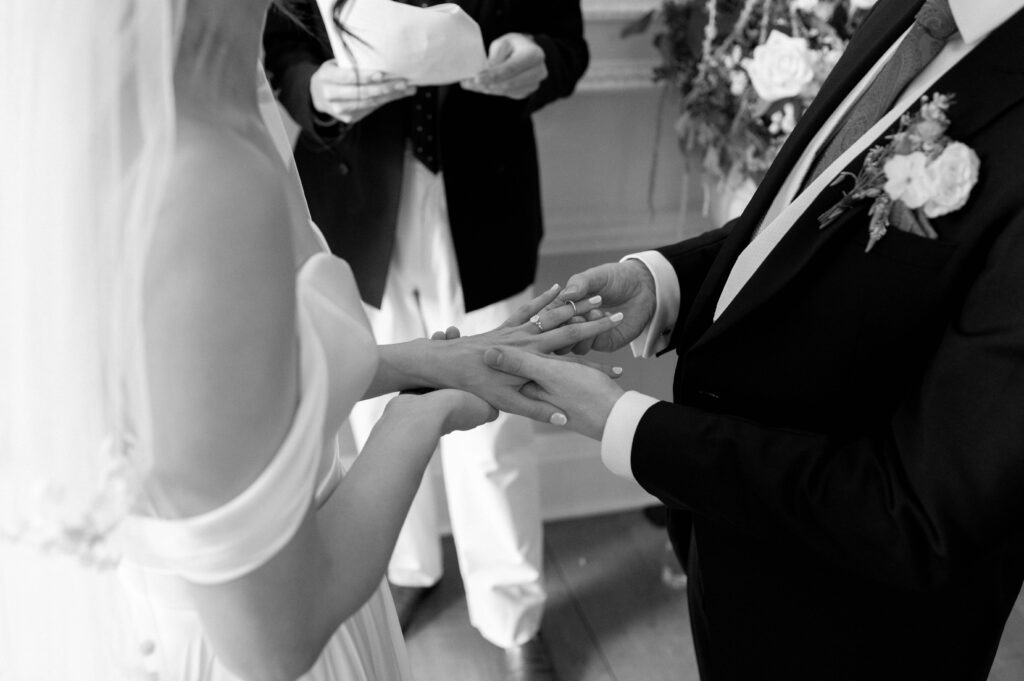 Black and white photo close up of Martin putting a ring on Charlie's finger.