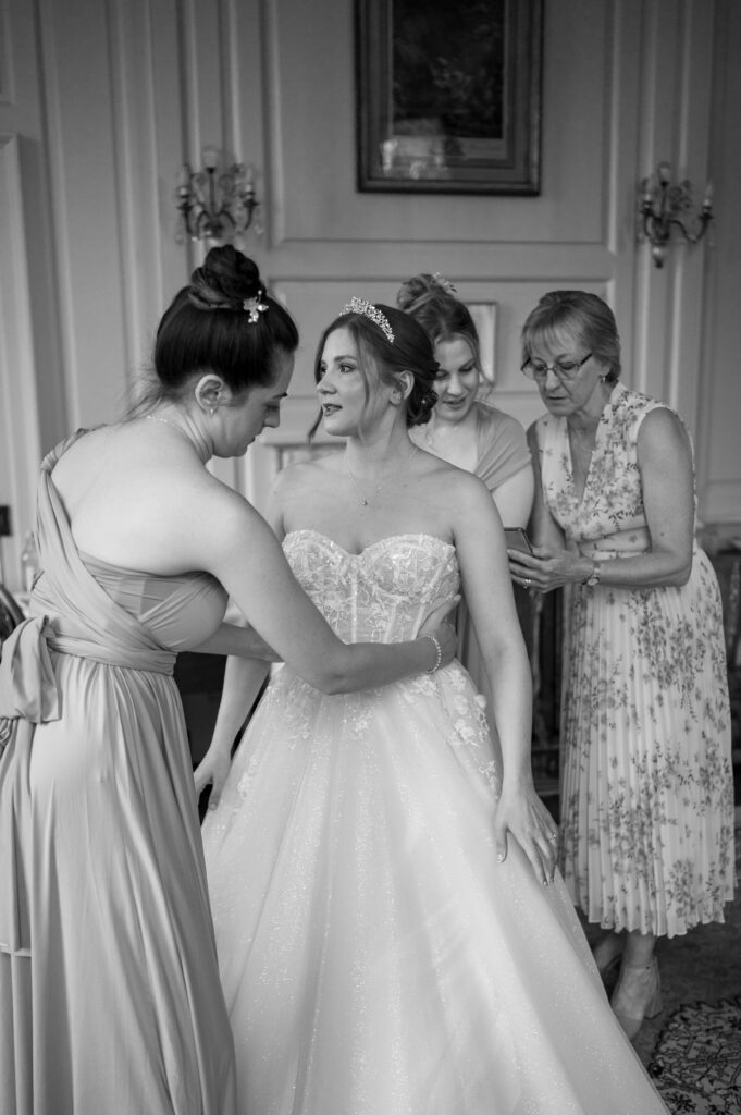 Amanda’s mum and bridesmaids helping her into her wedding dress, creating a heartwarming and supportive moment of love and togetherness.