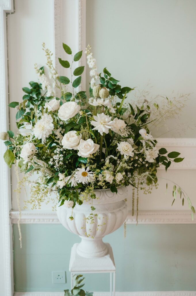 Close up of green and white floral arrangement in a vase in the ceremony room.