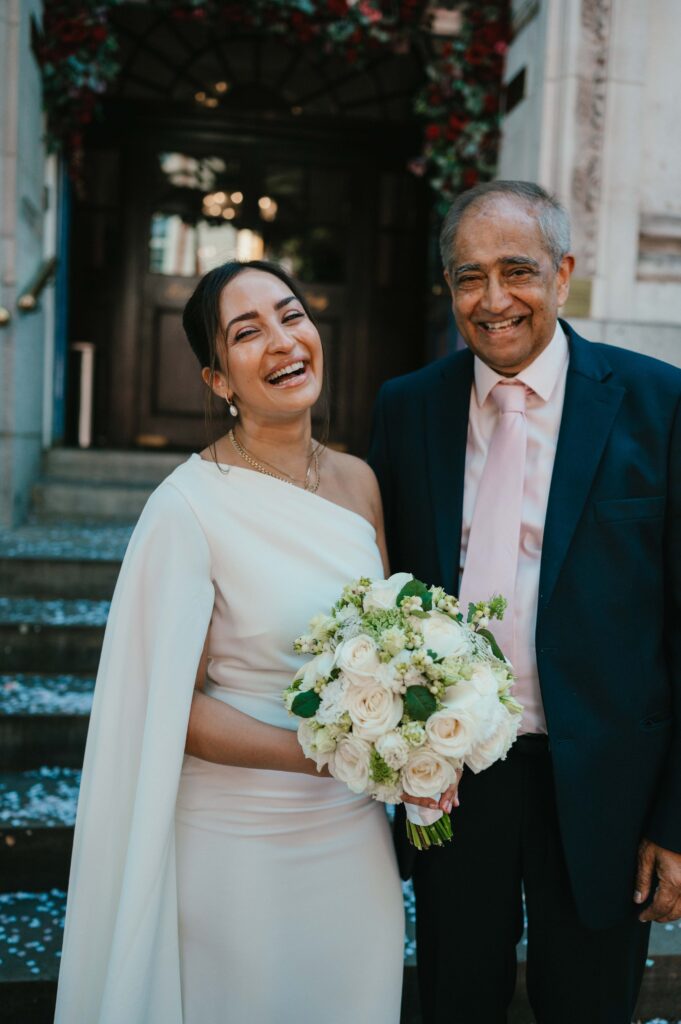 Candid photo of the bride and father of the bride laughing at the camera. 