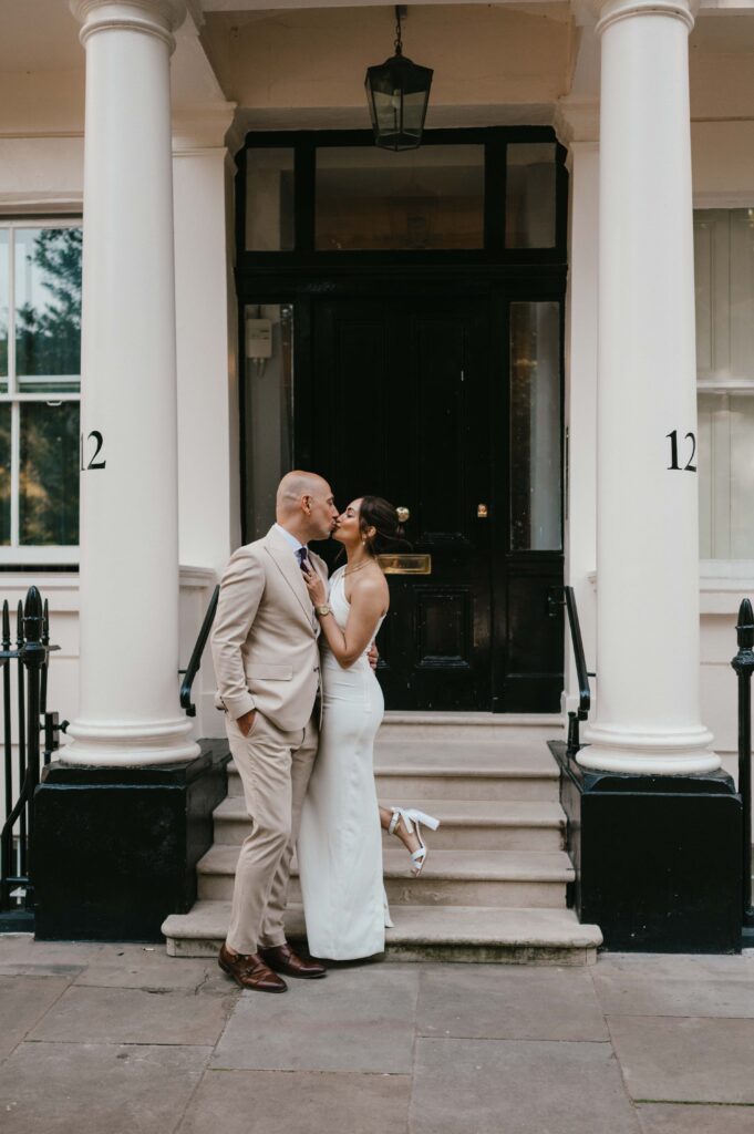 Raissa and Vasileios share a quiet moment in front of a white townhouse at Warwick Square, framed by elegant black railings.