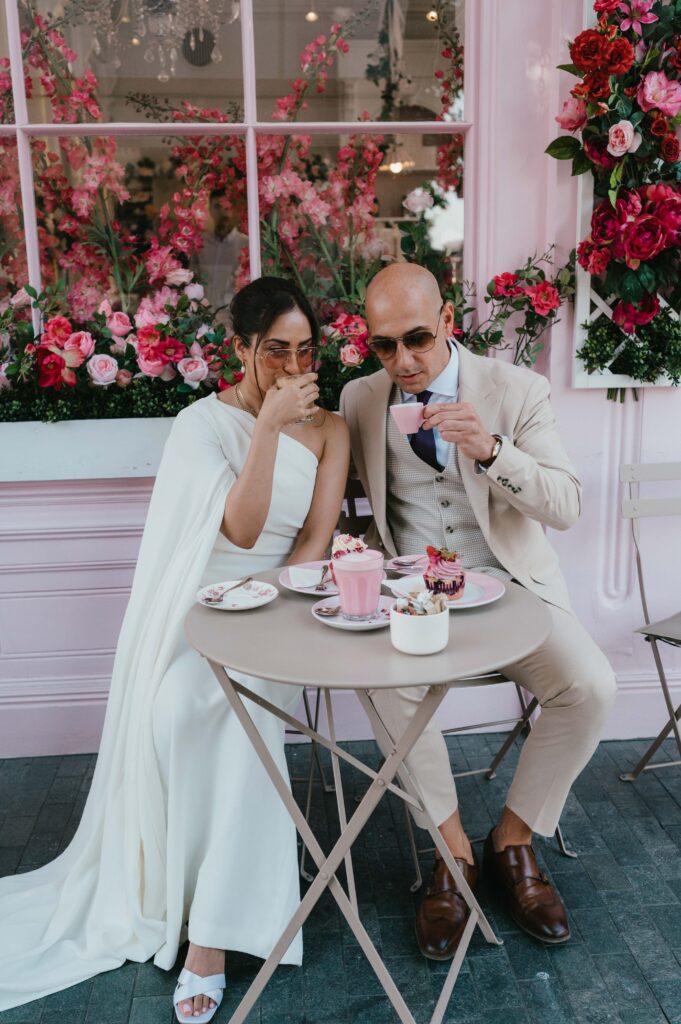 Sitting at a dainty table adorned with pastel treats, Raissa and Vasileios savor their drinks amidst the whimsical charm of Peggy Porschen Café.