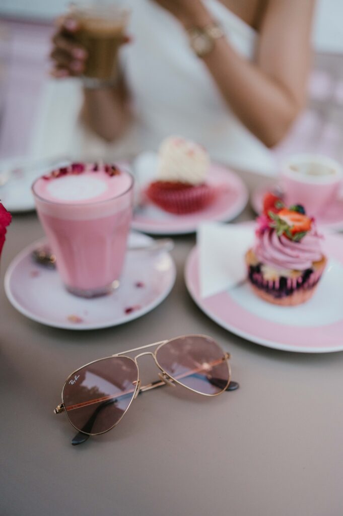 A detail shot of Raissa’s sunglasses resting on their café table, with their coffee cups and cake plates in the background.