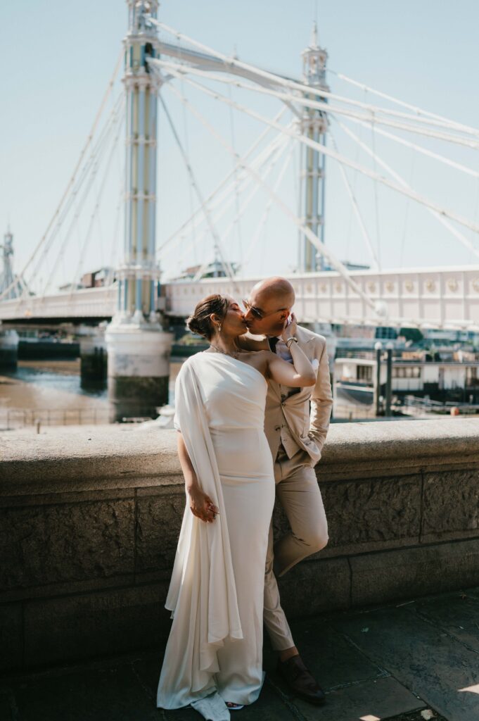 Raissa and Vasileios pause for a kiss set against the ornate railings of Albert Bridge.