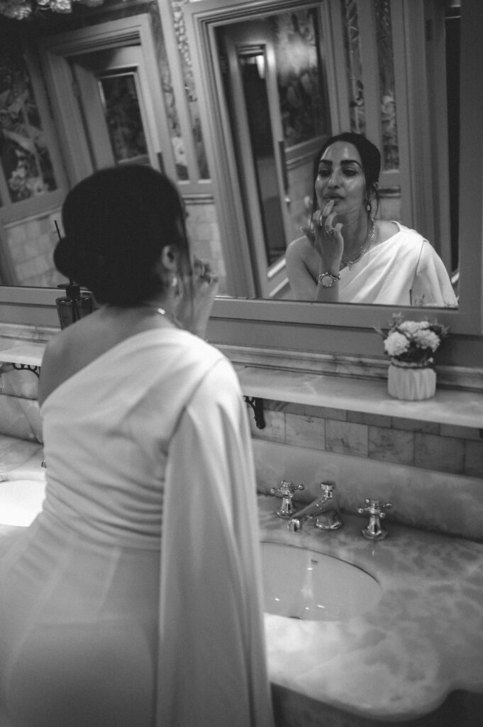 Raissa putting lipstick on looking in the mirror in the bathroom of The Ivy Chelsea. 